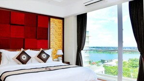 A hotel room with a large bed, a red headboard, a view of a body of water, and a balcony with curtains. - Moonlight Hotel Hue (Hue)