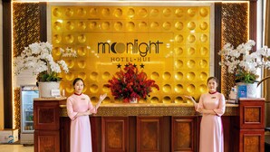 A reception desk with a 'Moonlight Hotel-Hue' sign, two attendants, and decorative plants. - Moonlight Hotel Hue (Hue)