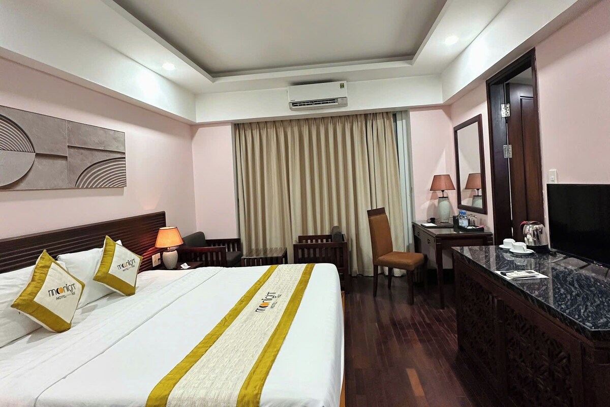 A hotel room with a bed, a desk, a chair, a television, and a mirror.