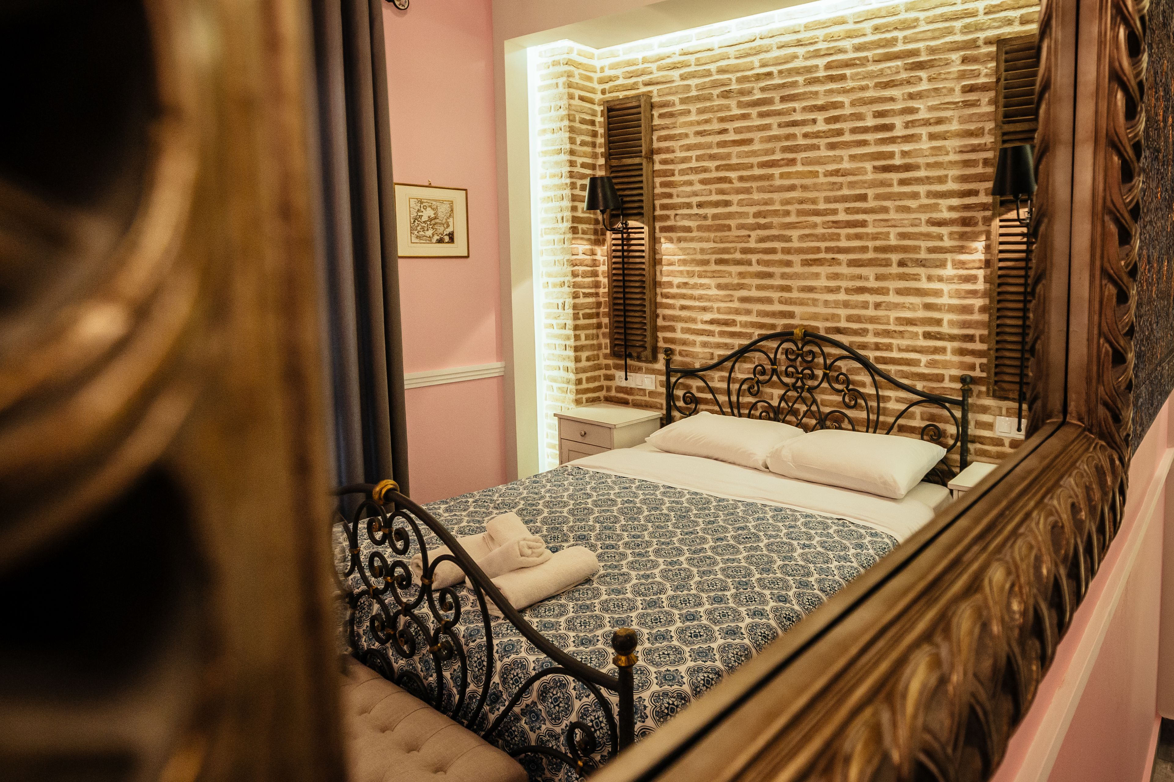 Une chambre avec un mur décoré d’un motif en briques, un lit recouvert d’une couvre-lit à motifs et une table de chevet avec une lampe.