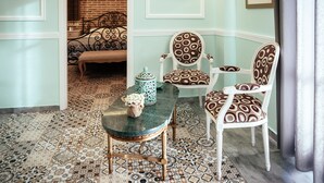 Una habitación con baldosas de diseño, una mesa de mármol verde y dos sillas con motivos.