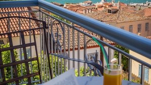 Un balcón con vistas a un pueblo costero, un libro y un vaso de zumo de naranja.
