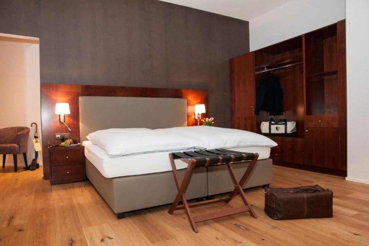 Un dormitorio moderno con una cama, lámparas de noche, un armario de madera y suelo de madera.