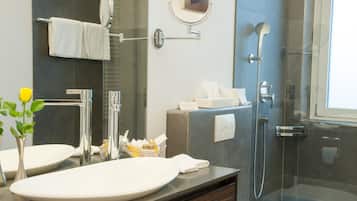 Un baño moderno con un espejo grande, un lavabo, una ducha y una zona de ducha con paredes de vidrio.