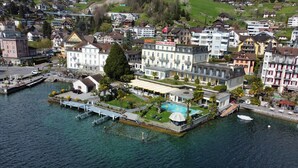 Een hotel aan het water met een zwembad, een steiger en weelderige begroeiing.