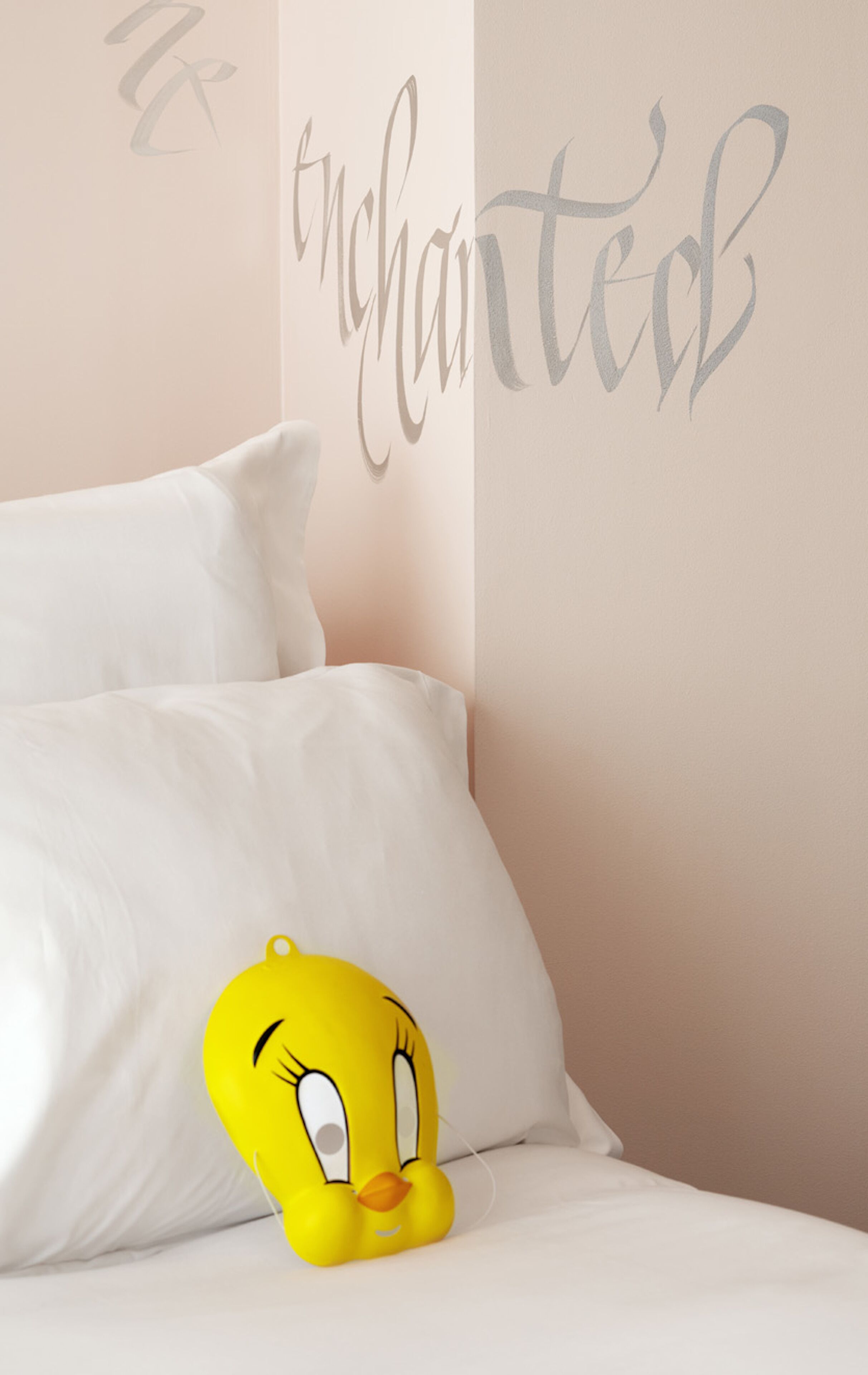 A bed with white bedding and a yellow plush toy.