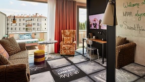 A modern hotel room with a balcony, a desk, a chair, and a sofa. - Mama Shelter Lyon (Lyon)