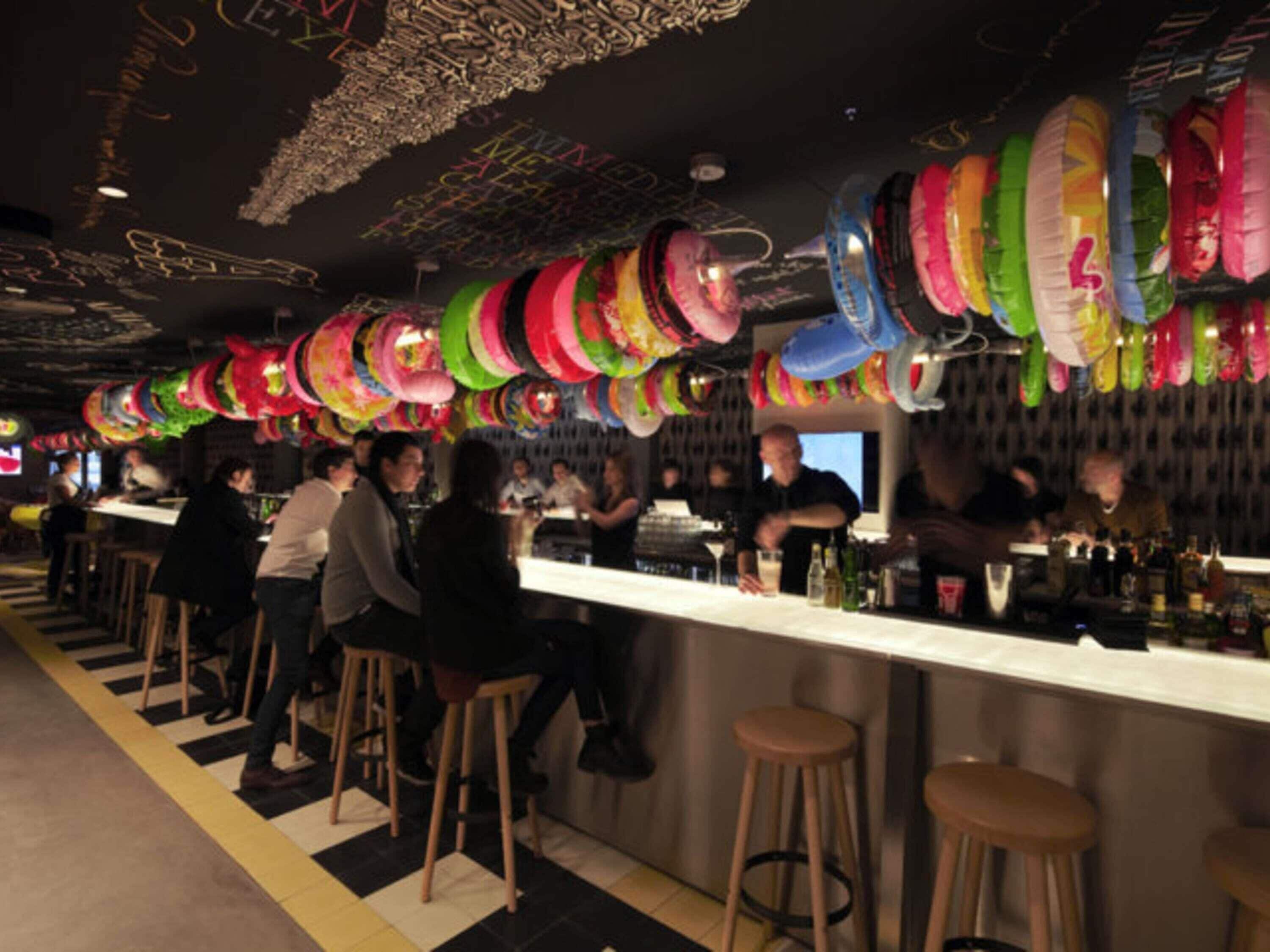 Zona de bar con taburetes y mostrador, decorada con objetos circulares colgantes.
