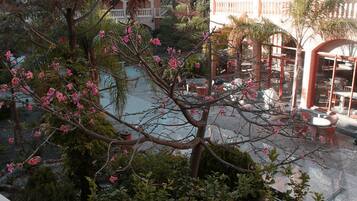Une cour avec une piscine, des sièges d’extérieur et un arbre aux fleurs roses.