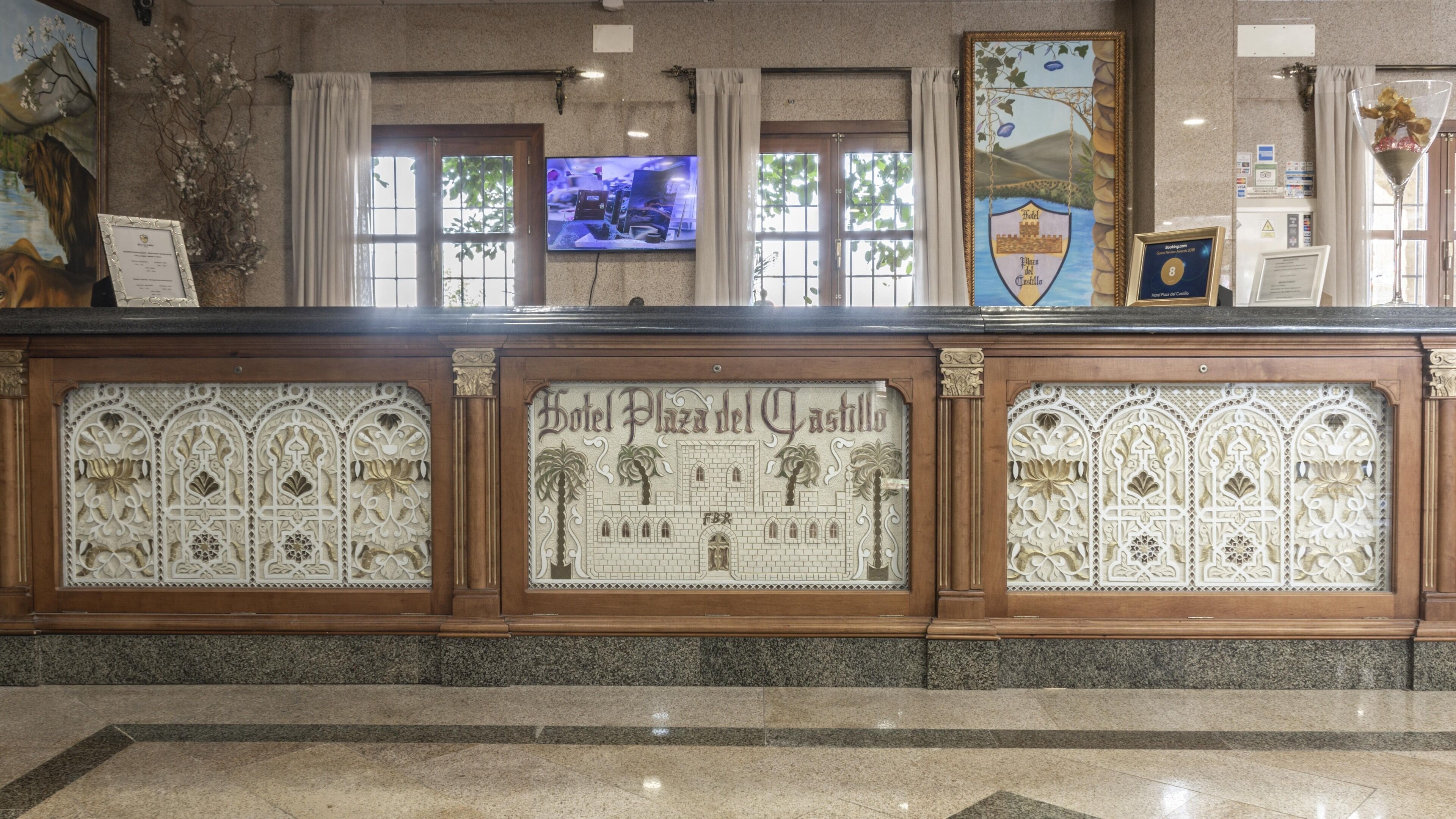 Una reception con elaborate decorazioni intagliate e una insegna con la scritta "Hotel Plaza del Castillo".