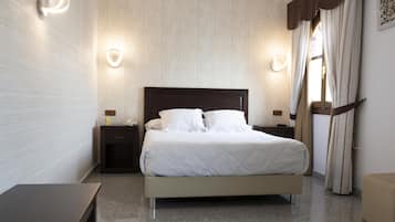 A neatly arranged bedroom with a bed, bedside tables, and wall sconces.