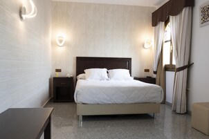 A neatly arranged bedroom with a bed, bedside tables, and wall sconces.