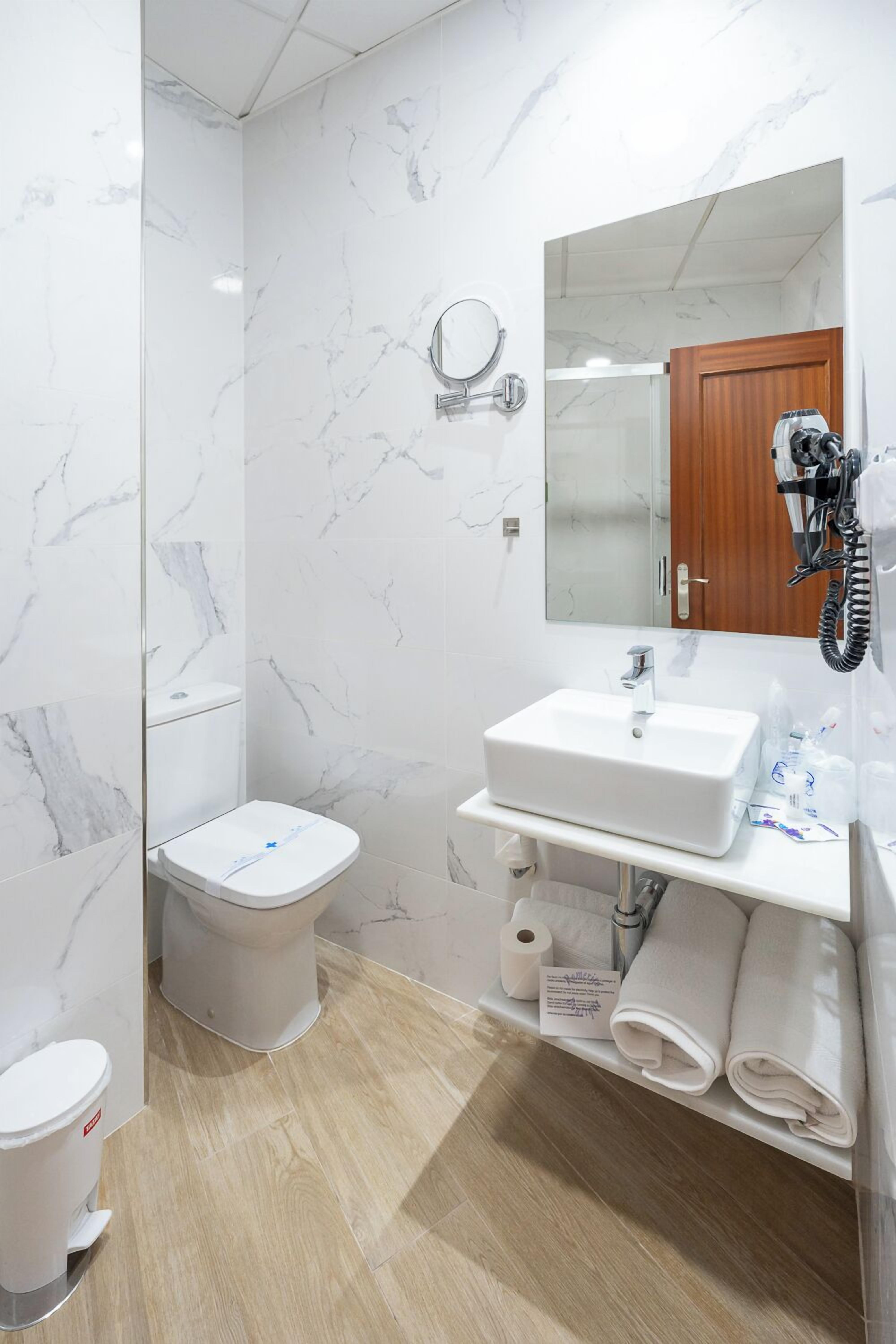 A modern bathroom with a toilet, sink, and mirror.