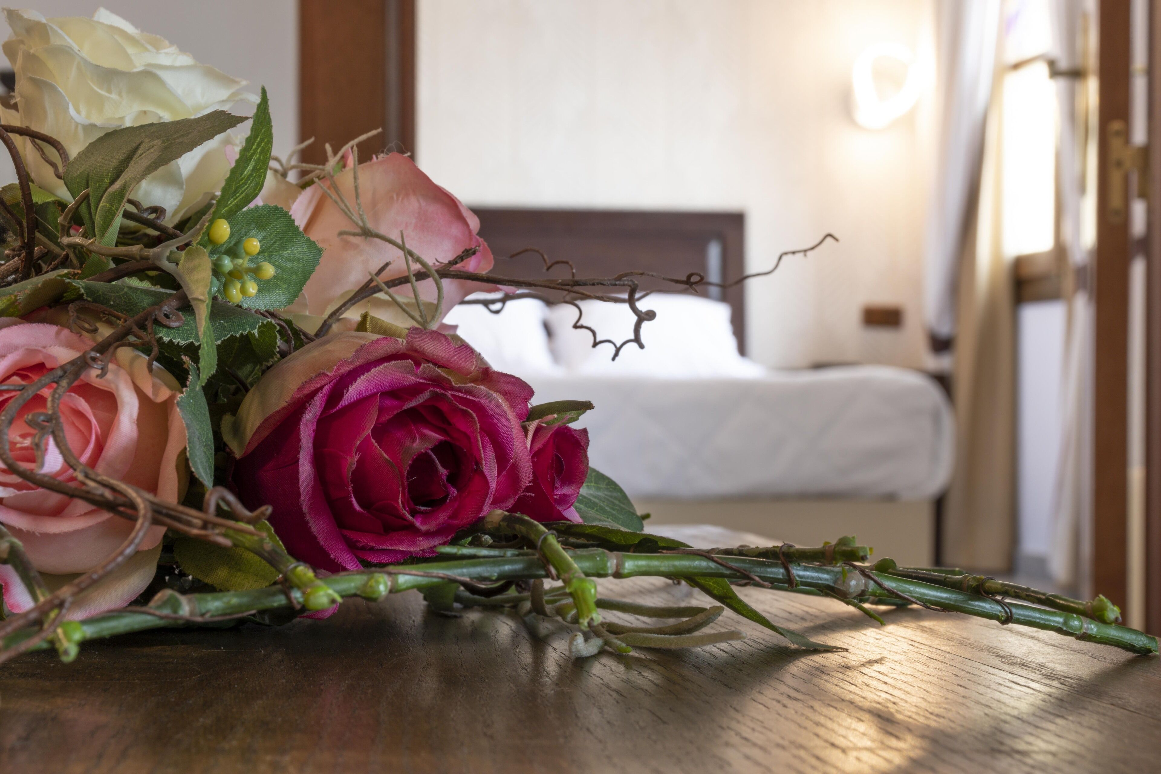 Ein Rosenstrauß auf einem Holztisch in einem Hotelzimmer.