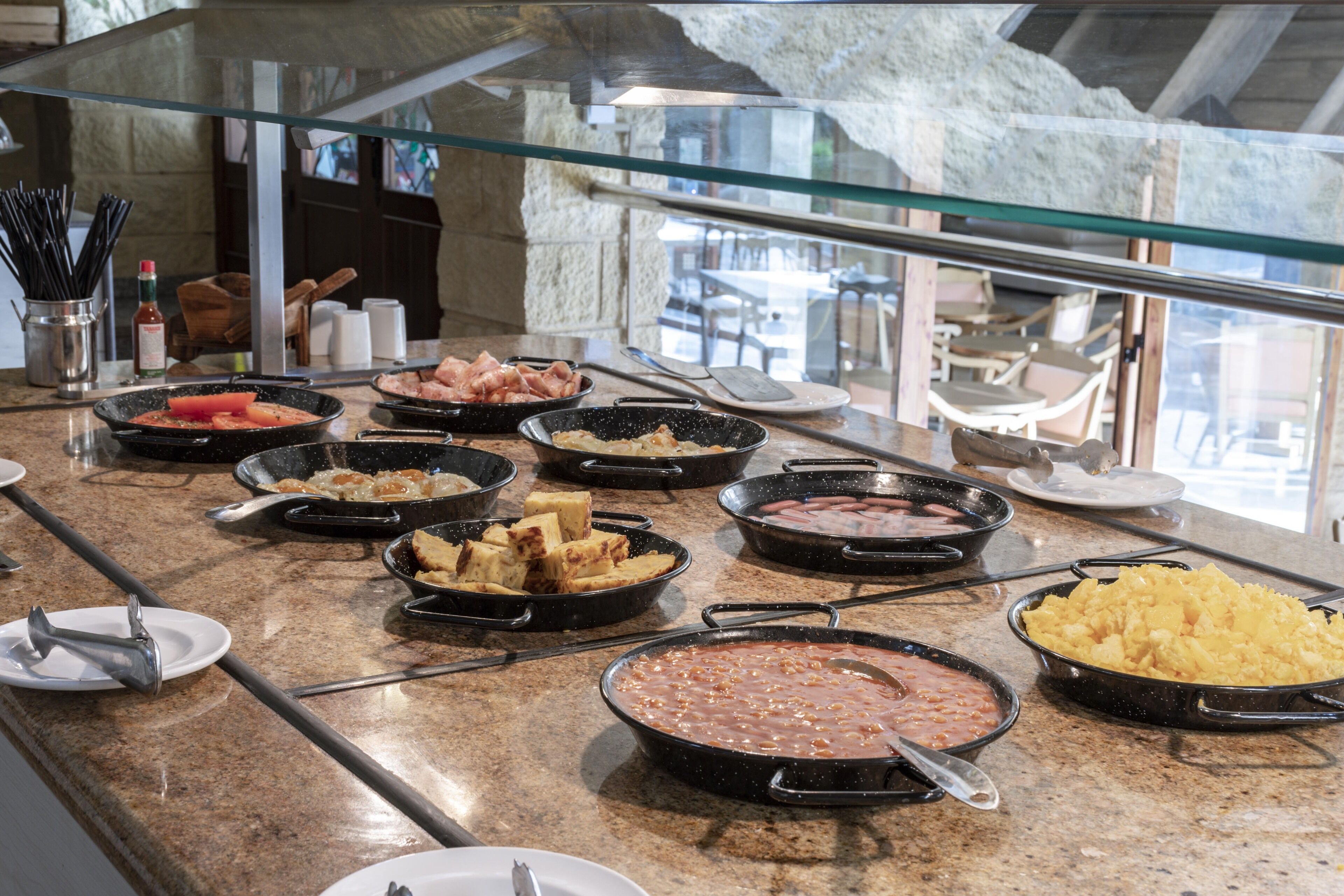 Een buffet met diverse gerechten, waaronder vlees, groenten en sauzen, gepresenteerd op een granieten aanrecht.