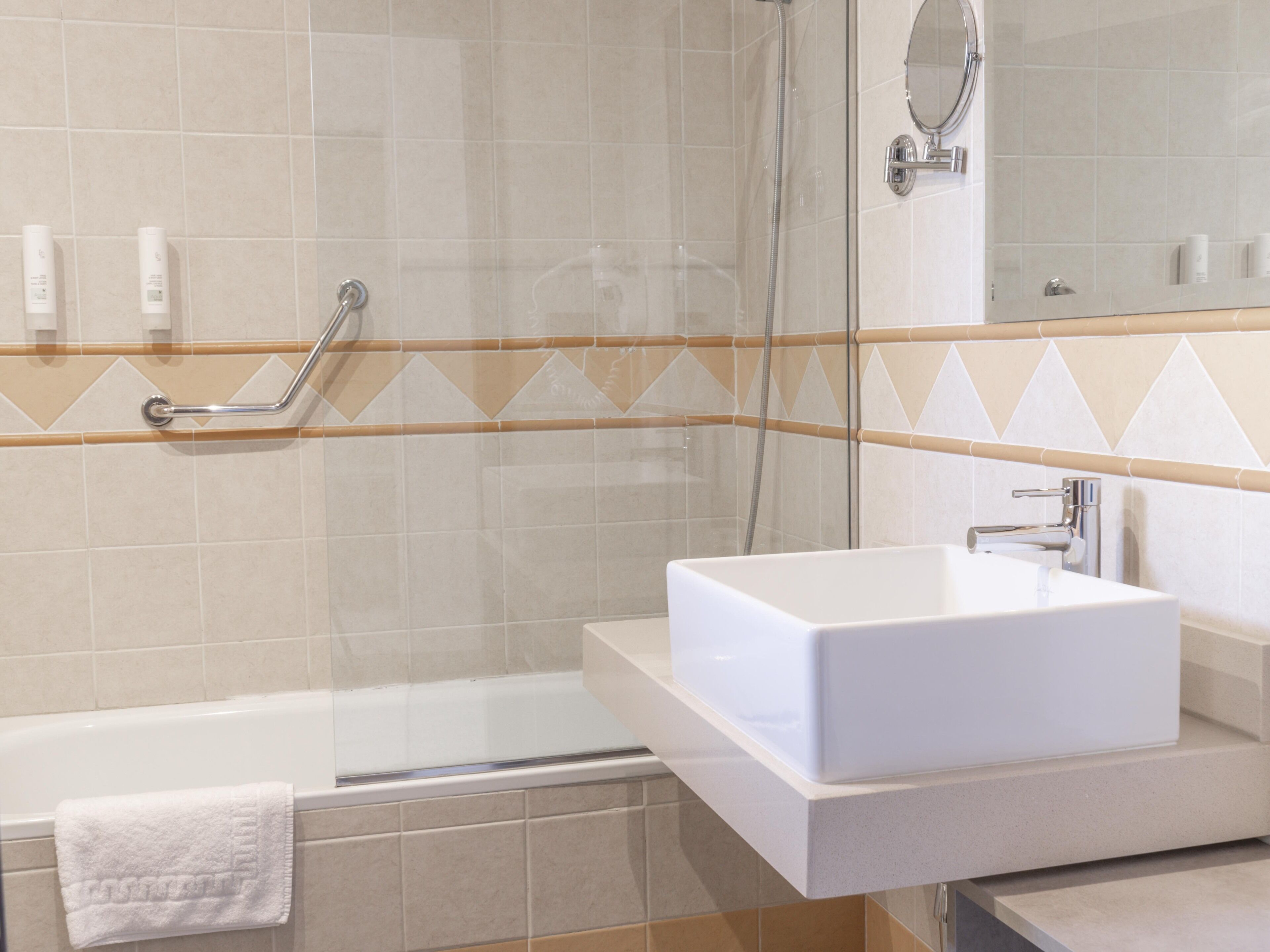 A modern bathroom with a glass-enclosed shower, a white sink, and a mirror.