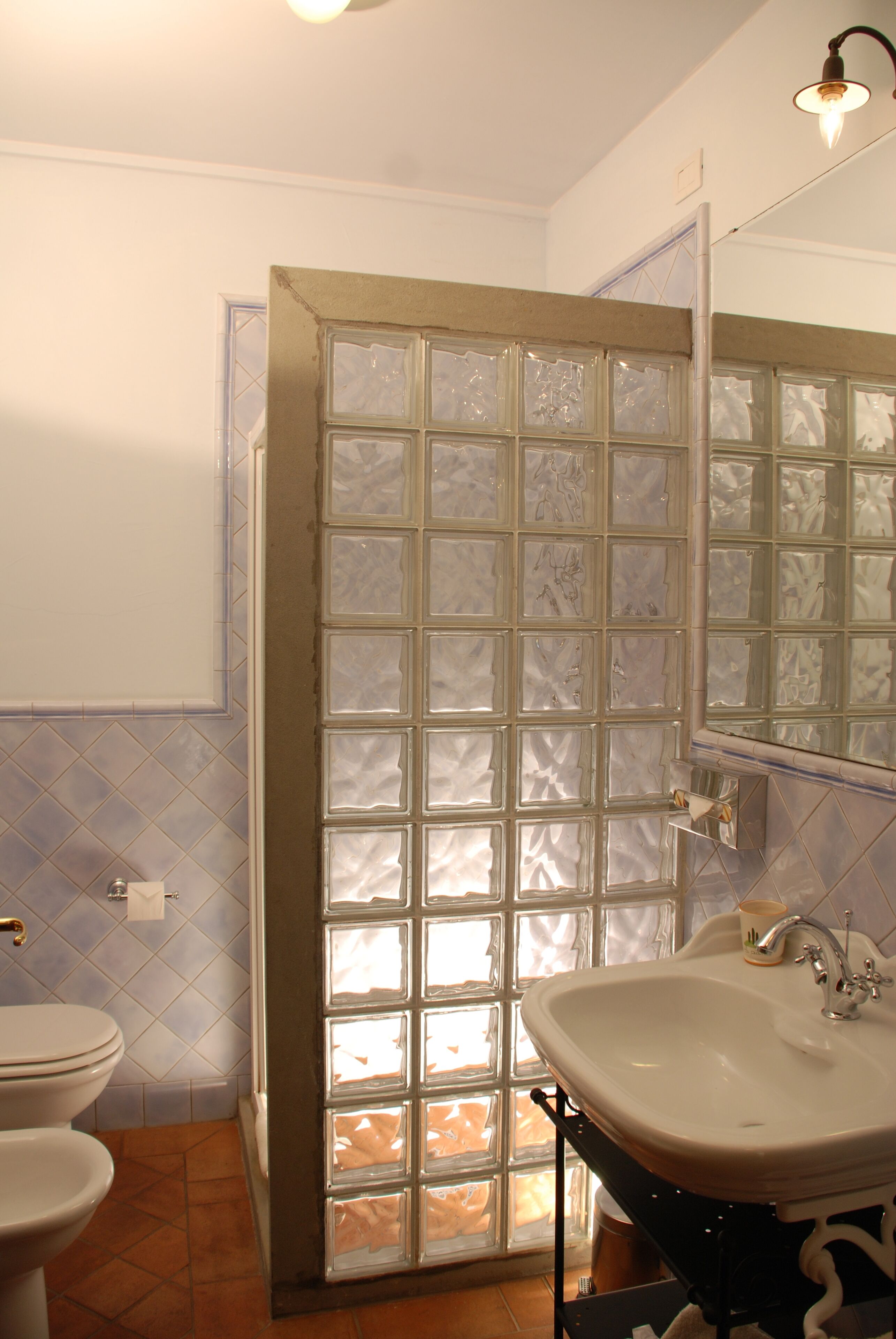Une salle de bain équipée de toilettes, d’un lavabo et d’une porte de douche en verre dépoli.