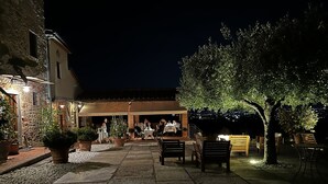 Un patio al aire libre con suelo de piedra, plantas en macetas y mesas y sillas dispuestas para comer.