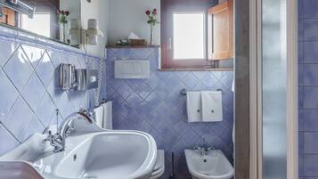 Un baño con un lavabo grande, un bidé y una ventana.
