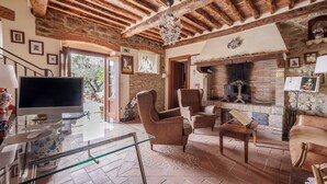 Una sala rústica con vigas de madera a la vista, una chimenea y asientos cómodos.