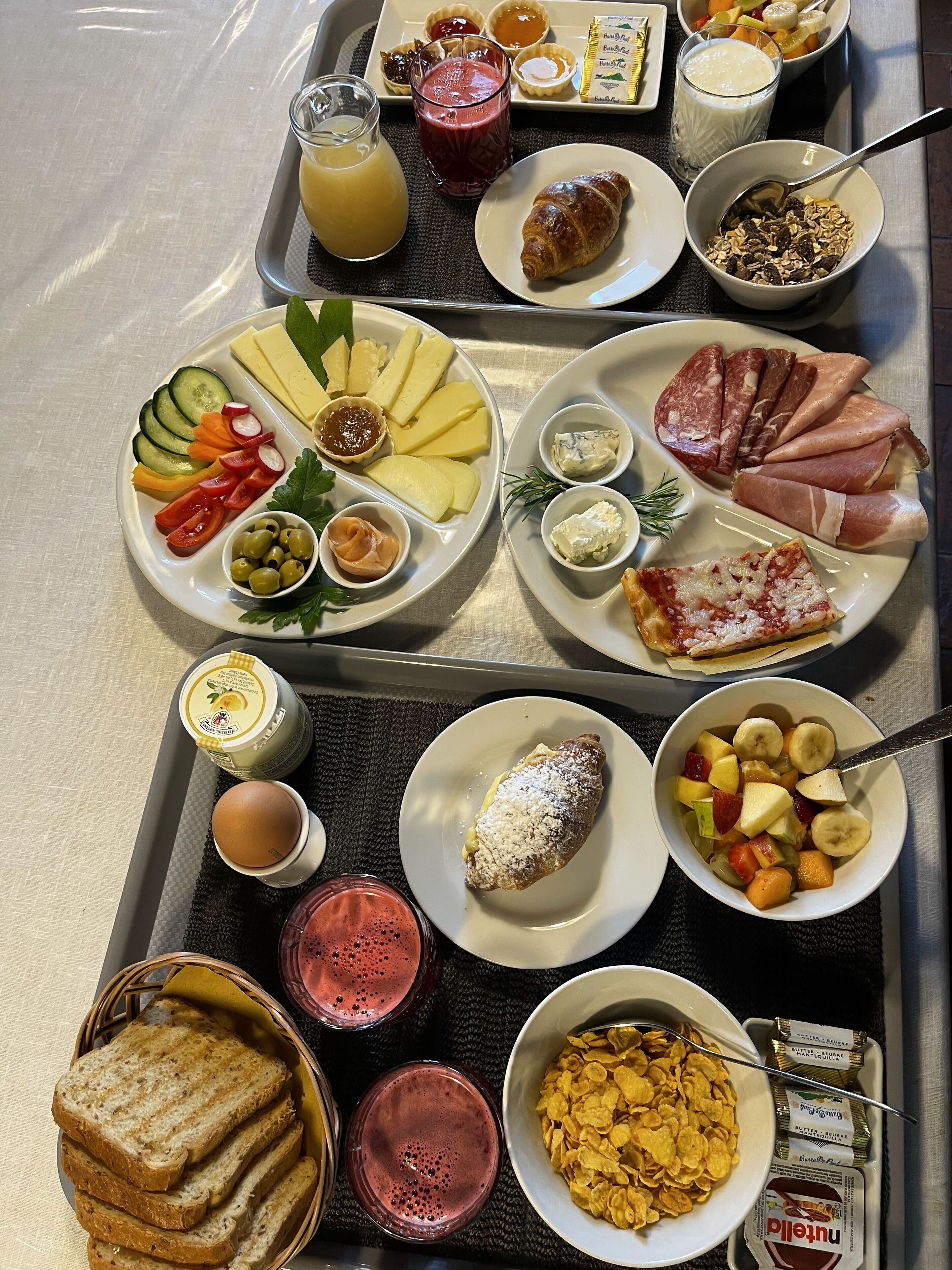 Un vassoio per la colazione con diversi cibi, tra cui pane tostato, cereali, frutta e pasticceria.