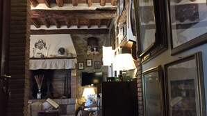 Una habitación acogedora con chimenea de piedra, vigas de madera y cuadros en las paredes.