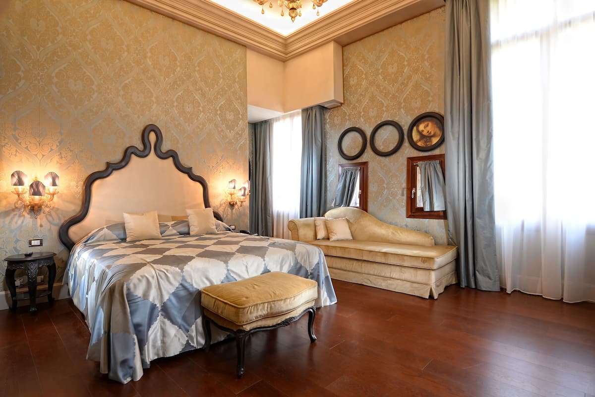 A bedroom with a large bed, a sofa, and a small table.