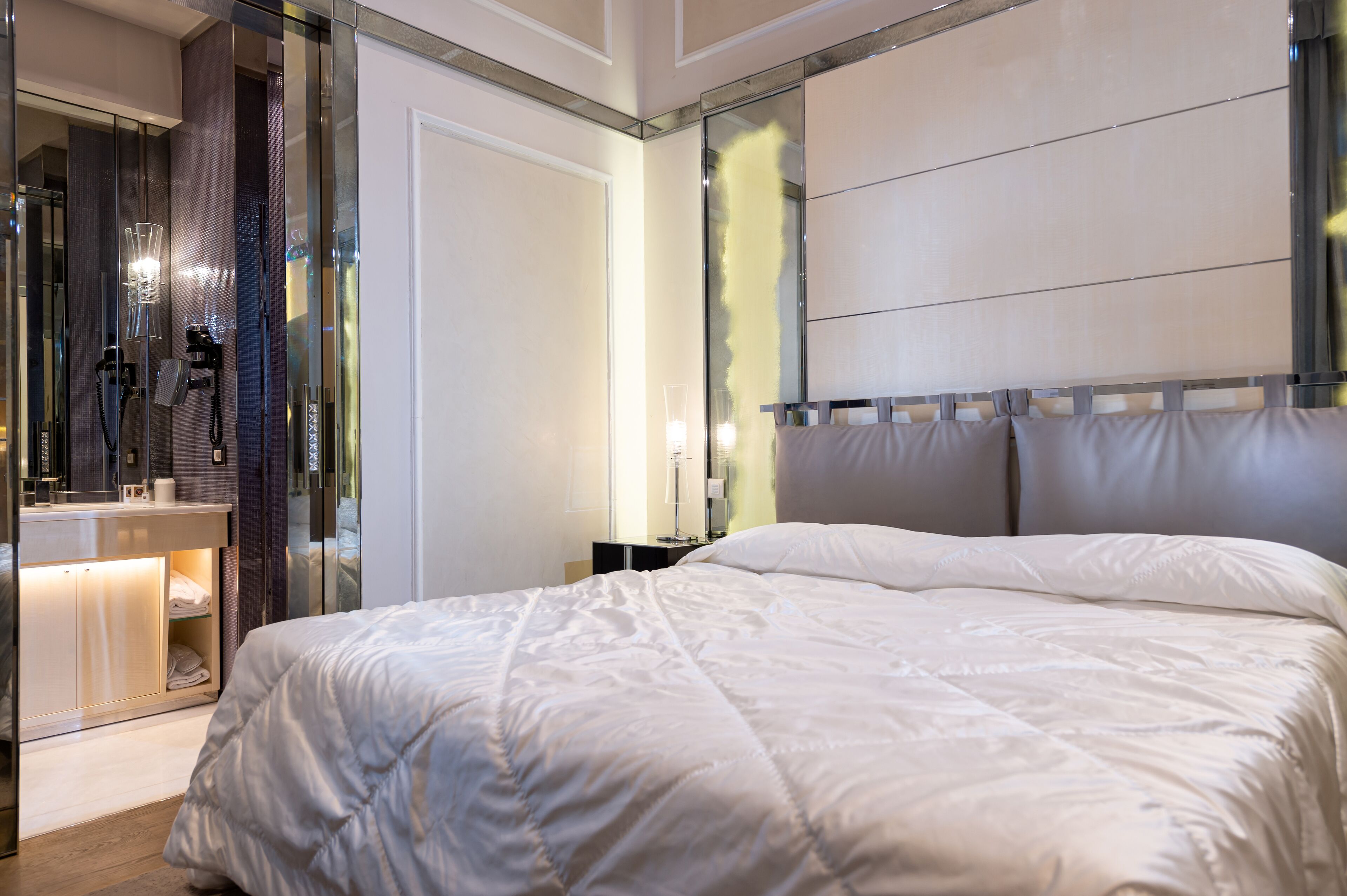Une chambre moderne avec un grand lit, une douche en verre et une coiffeuse avec un miroir.