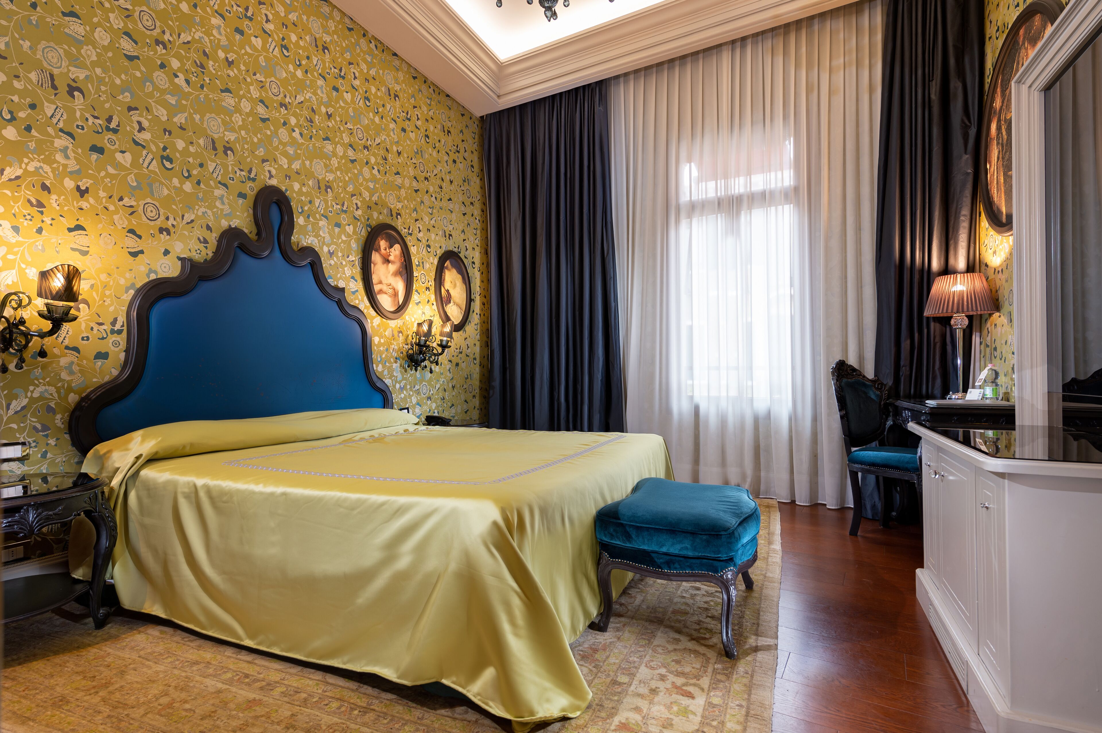 A hotel room with a large bed, a desk, a chair, and a mirror.
