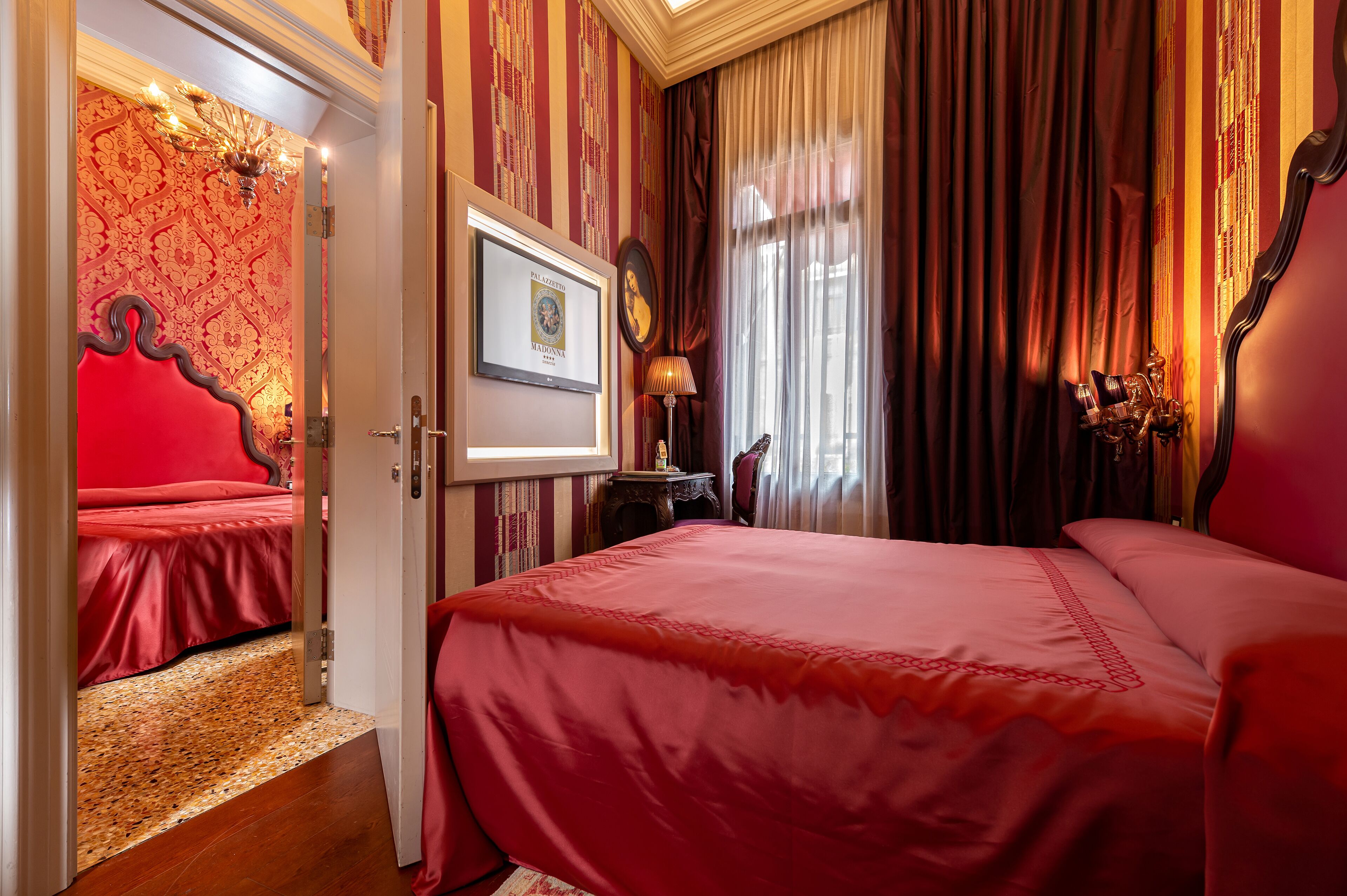 Une chambre d’hôtel avec un grand lit, un tableau encadré au mur et un lustre.