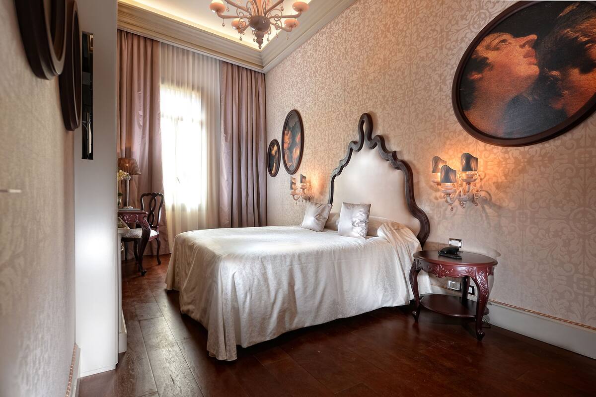 A bedroom with a large bed, a nightstand, and a wall-mounted lamp.