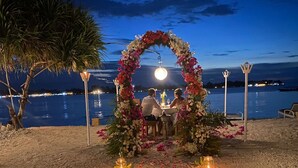 Un cadre romantique en plein air, avec une arche fleurie et des bougies, sur une plage au clair de lune.
