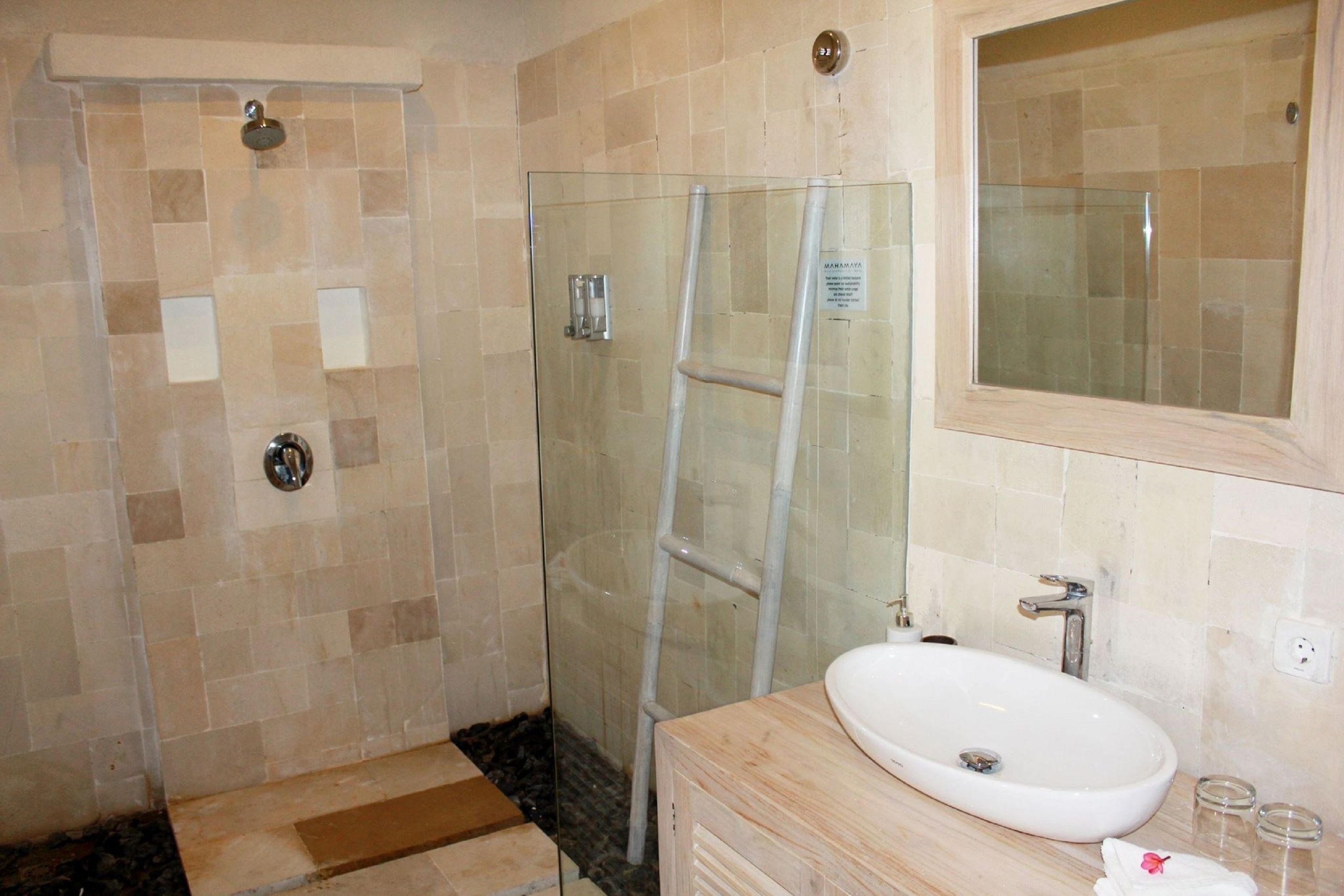 A bathroom with a glass shower enclosure, a sink, and a mirror.