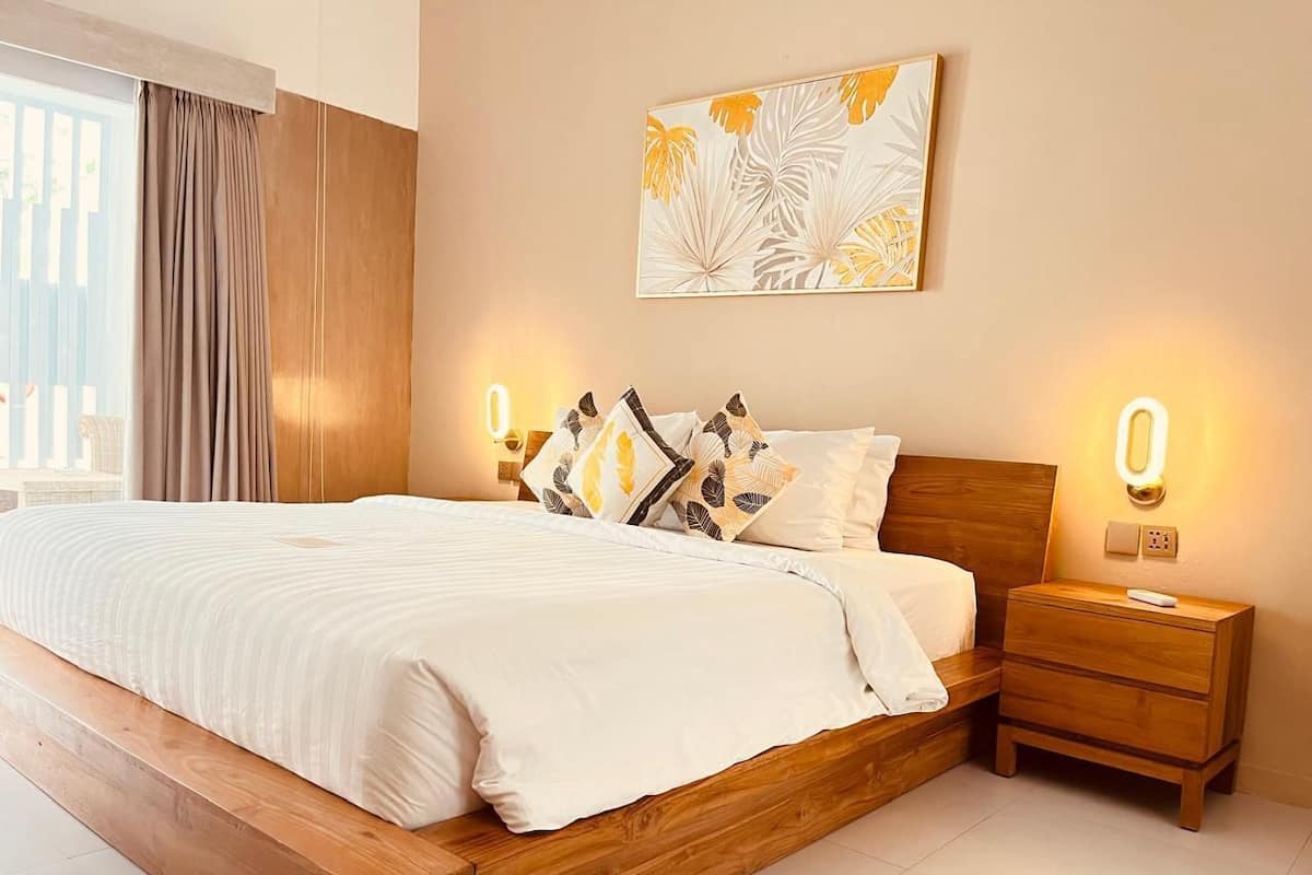 Un dormitorio moderno con una cama de madera, ropa de cama blanca y una mesita de noche con una lámpara.