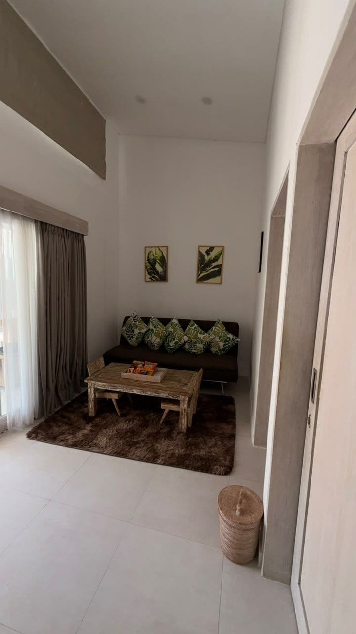 Ein Wohnzimmer mit einer Couch, einem Couchtisch, einem Teppich und einer Tür.