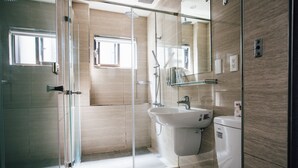 A modern bathroom with a glass shower enclosure, a sink, and a toilet. - Chingjing Inn (Taipei)