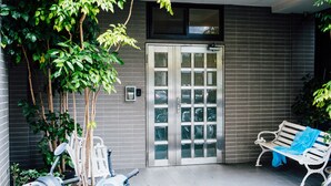 A gated entrance with a bench, potted plants, and a wall-mounted intercom. - Chingjing Inn (Taipei)