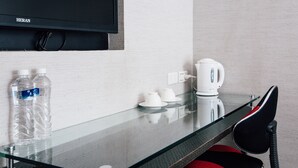 A hotel room with a glass table, two water bottles, a kettle, and a chair. - Chingjing Inn (Taipei)