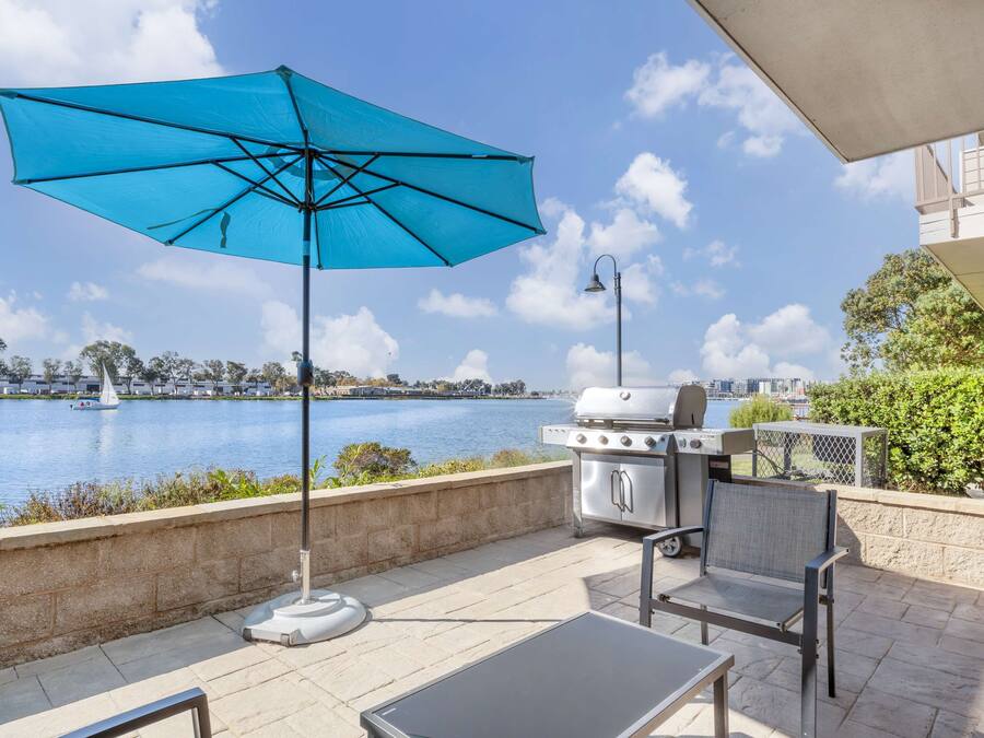 Eine Terrasss mit Grill, Sitzgelegenheit und Blick auf einen See.