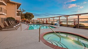Zona de piscina con sillones de descanso y vista a un cuerpo de agua.