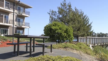 A multi-story building with balconies, a picnic table, and a wooden bridge.