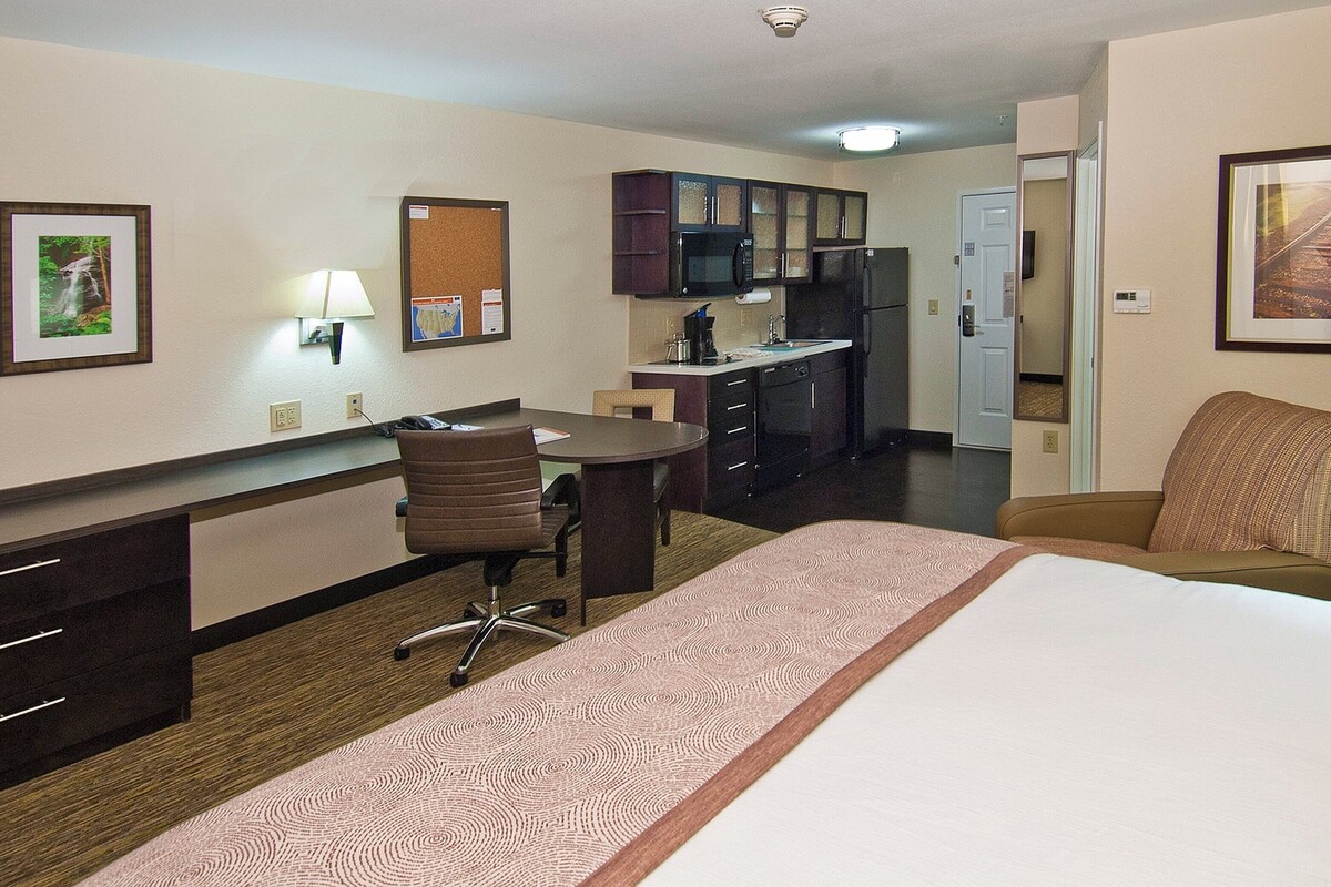 Une chambre d’hôtel équipée d’un lit, d’un bureau, d’une chaise, d’un four à micro-ondes, d’un réfrigérateur et d’une porte donnant accès à une salle de bain.