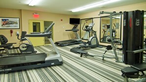 Een hotel fitnessruimte met loopbanden, een hometrainer en krachtapparaten.