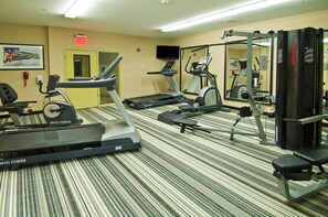 Une salle de sport d’hôtel équipée de tapis de course, d’un vélo d’appartement et d’appareils de musculation.