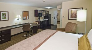Une chambre d’hôtel comprenant un lit, un bureau, une chaise, une kitchenette et une salle de bain.