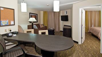 A hotel room with a conference table, a sofa, a TV, and a bed.