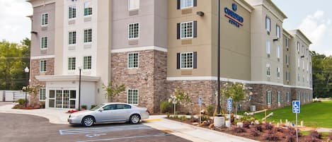 A hotel with a stone facade, multiple windows, and a parking lot with handicapped accessible spaces.