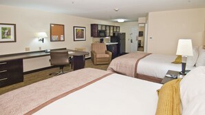 A hotel room with two beds, a desk, a chair, a kitchenette, and a bathroom.