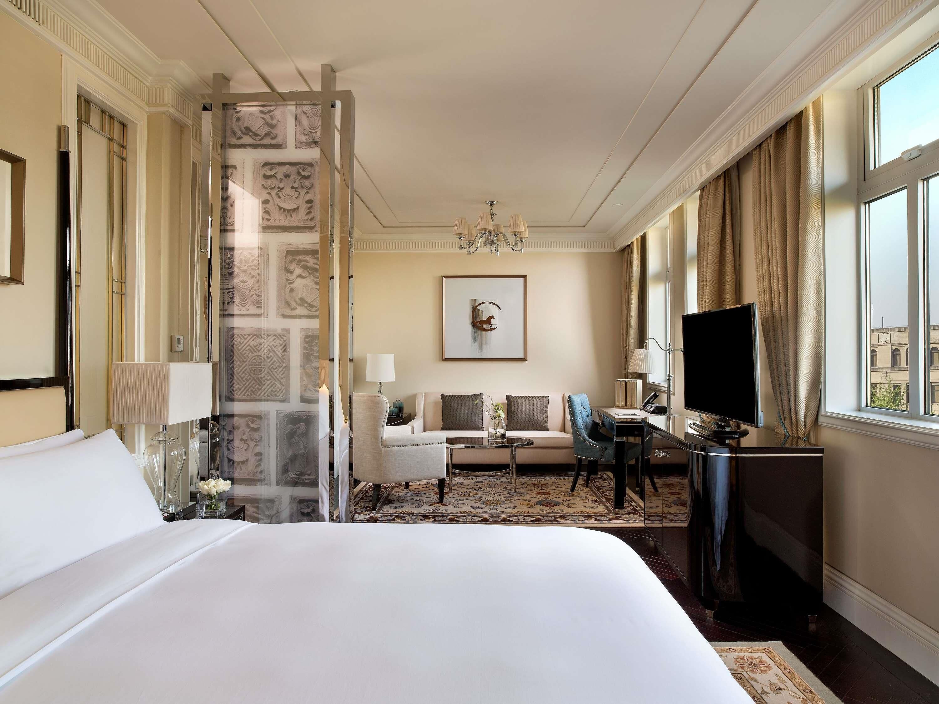 Habitació d'hotel amb un llit gran, un escriptori amb un ordinador, una cadira, un sofà i una televisió.