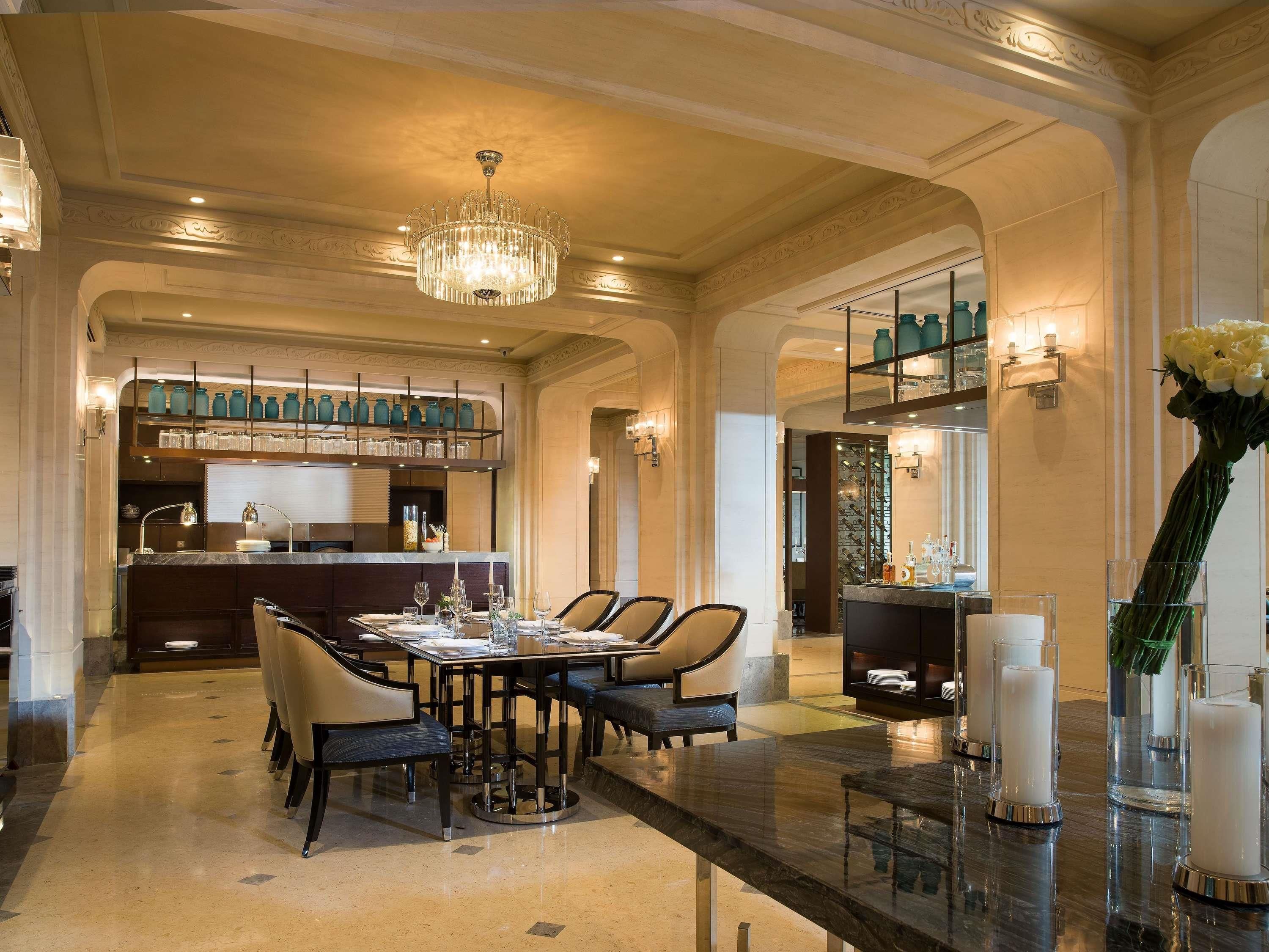 Ein eleganter Speisebereich mit einer Chandelierleuchtre, eine Bar mit Regalen voller Gläser und Blick in die Küche.